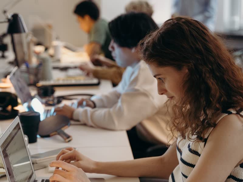 A row of colleagues working along a shared desk