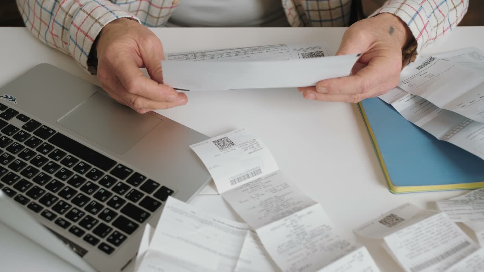 Invoices and receipts beside a laptop
