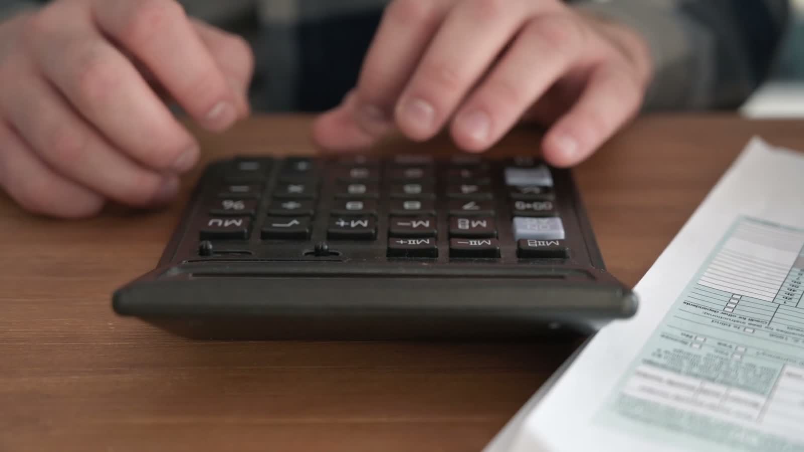 Hands working a calculator over a statement